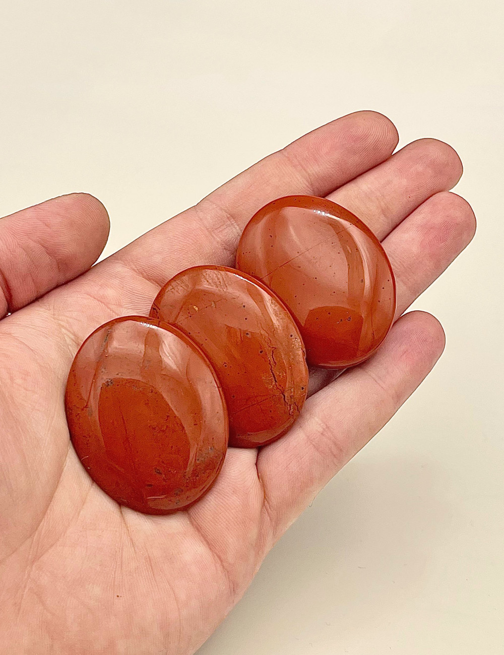 Rodado plano de Jaspe rojo natural  pulido – vista principal en mano