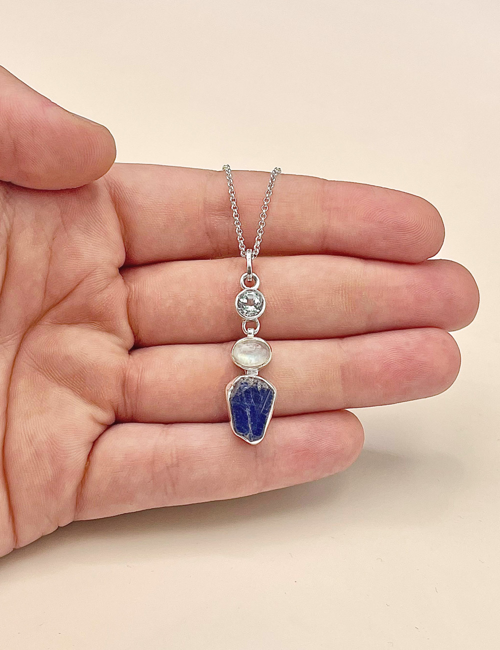 Colgante multimineral natural en plata con topacio azul, piedra de luna y tanzanita – vista en mano