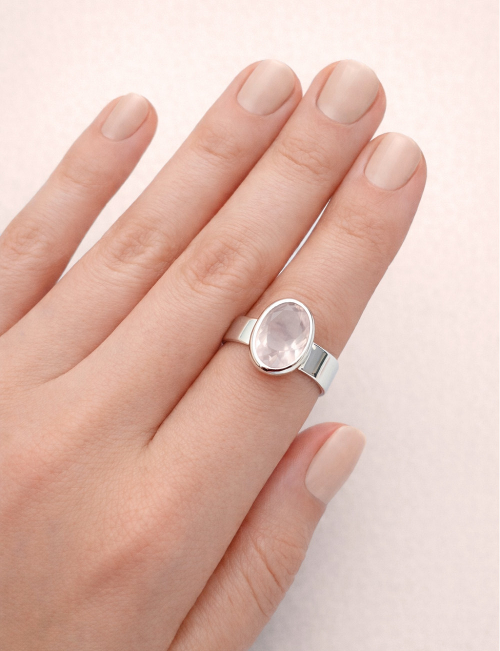 Anillo de cuarzo rosa natural tallado en plata en la mano