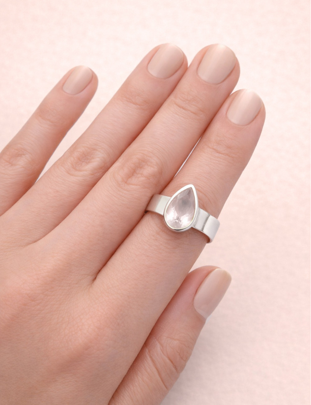 Anillo de cuarzo rosa natural tallado en plata en la mano