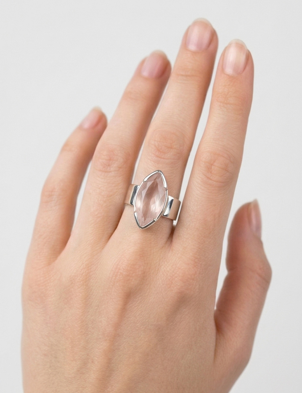 Anillo de cuarzo rosa natural tallado en plata en la mano